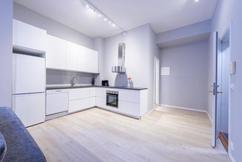 a kitchen with white cabinets and a wooden floor at Maya Apartments - Sentrum in Oslo