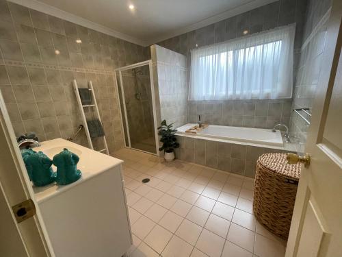 y baño con bañera, ducha y lavamanos. en Award winning - Open plan Coastal Beauty in Patonga Beach - Pet Friendly, en Patonga