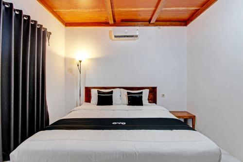een slaapkamer met een groot bed en zwarte gordijnen bij Capital O 93449 The Boekit Song Putri Resort in Wonogiri