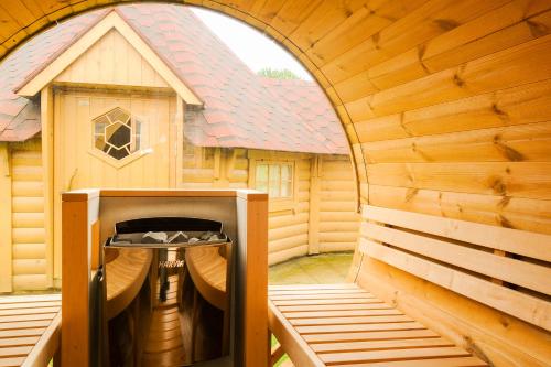 una gran sauna de madera con un edificio en el fondo en GITE MELODIE + Sauna Extérieur, en Gosnay