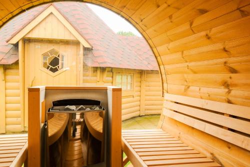 eine große Holzsauna mit einem Gebäude im Hintergrund in der Unterkunft GITE MELODIE + Sauna Extérieur in Gosnay