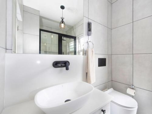 a white bathroom with a sink and a toilet at Kelly's Beachfront Apartments in Port Alfred