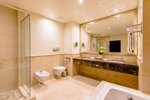 a bathroom with a sink toilet and a mirror at Southern Sun Sandton in Johannesburg