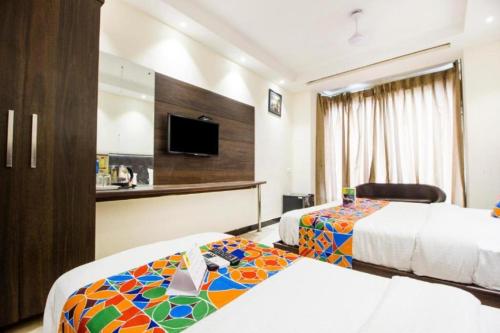 a hotel room with two beds and a flat screen tv at Hotel Le Continental in New Delhi