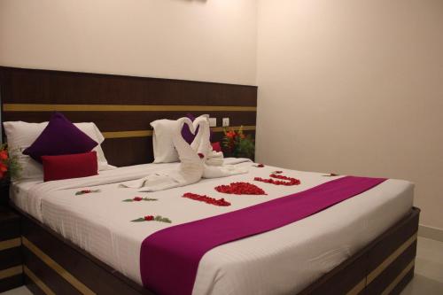 duże łóżko z czerwonymi różami i białymi butami w obiekcie Elgozo Hotel Dreams Parasise w mieście Yercaud