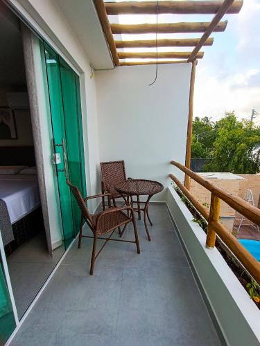 a balcony with two chairs and a table and a bed at Flats Marina Maragogi in Maragogi