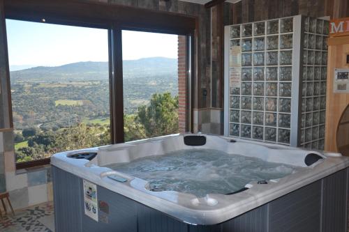 a bath tub in a room with a large window at Casa Rural & SPA Mirador Gredos in Guijo de Ávila
