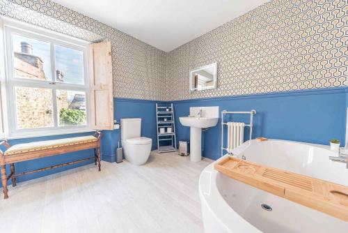 Baño azul con bañera y lavamanos en Tastefully decorated, family friendly property, central Kirkby Lonsdale, parking and EV charger, en Kirkby Lonsdale