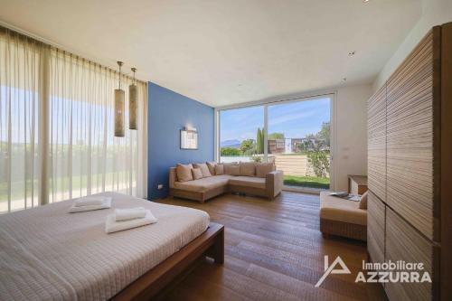 1 dormitorio con cama, sofá y ventana grande en Villa Madabà - Immobiliare Azzurra, en Bardolino