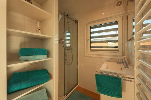 een badkamer met groene handdoeken, een wastafel en een douche bij Hausboot Möwenschiss in Klitten