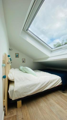 - une chambre avec une lucarne et un lit avec une fenêtre dans l'établissement La casita, entre mer et campagne, à Douvres-la-Délivrande