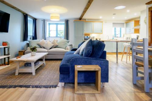 sala de estar con sofá azul y cocina en Lamorna, en Mawnan Smith