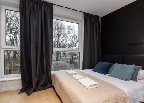 a bedroom with a large bed with two windows at Quercus Deluxe Studio in Gdańsk