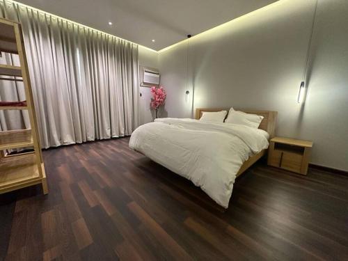 a bedroom with a large white bed and wooden floors at تربل فور سويت - شقة في فيلا in Al Başar
