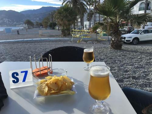 una mesa con dos vasos de cerveza y patatas fritas en HH Apartamento La Herradura Playa, en La Herradura