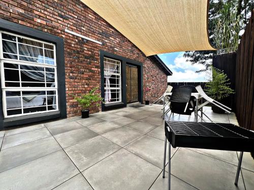 a patio with chairs and a brick building at Lincoln Moon Guesthouse in Graskop