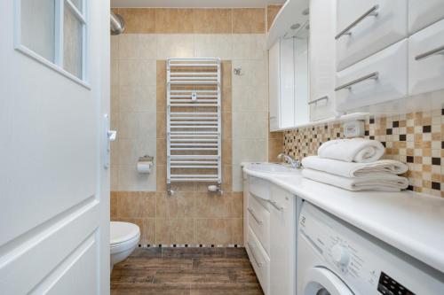 La salle de bains blanche est pourvue de toilettes et d'un lavabo. dans l'établissement Jantar Apartamenty Kołobrzeg - Przy Rzece, à Kołobrzeg