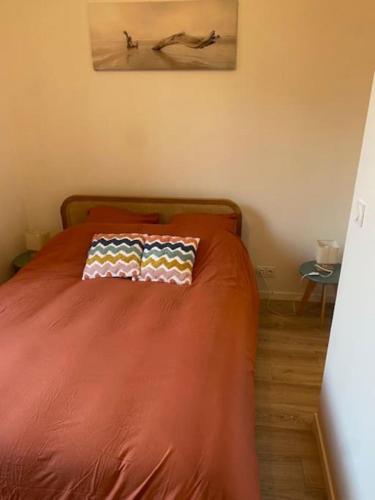 - un lit avec une couette en orange et un oreiller dans l'établissement Agréable T2 en centre-ville, à Vannes