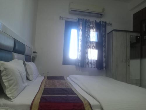 a white bedroom with a bed and a window at Gurjeet Hotel by Naavagat in Amritsar