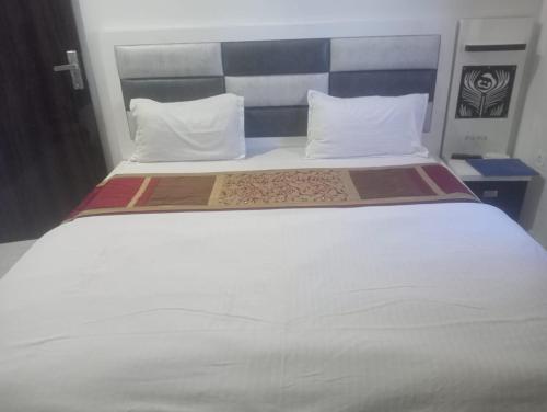 een groot wit bed met 2 kussens erop bij Gurjeet Hotel by Naavagat in Amritsar