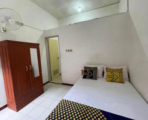 um pequeno quarto com uma cama com almofadas amarelas e azuis em SPOT ON 93644 Sederhana Homestay em Sidoarjo