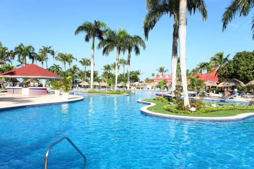 a swimming pool at a resort with palm trees at Bahia Principe Grand La Romana - All Inclusive in La Romana