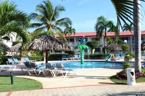 a resort with a pool with chairs and palm trees at Bahia Principe Grand La Romana - All Inclusive in La Romana