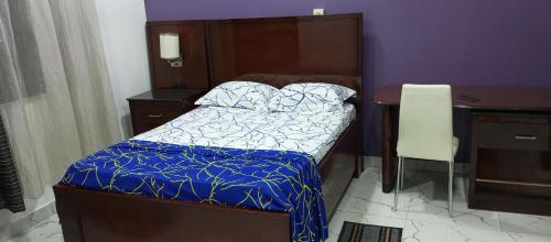 een kleine slaapkamer met een bed en een bureau bij RESIDENCE DE GLOIRE in Cotonou