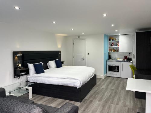 a bedroom with a large bed and a kitchen at Pinewood Guest House in Iver