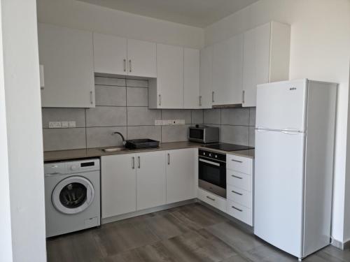 uma cozinha branca com um frigorífico e uma máquina de lavar louça em Διαμερισμα 1 υπνοδωματίου em Aglantzia