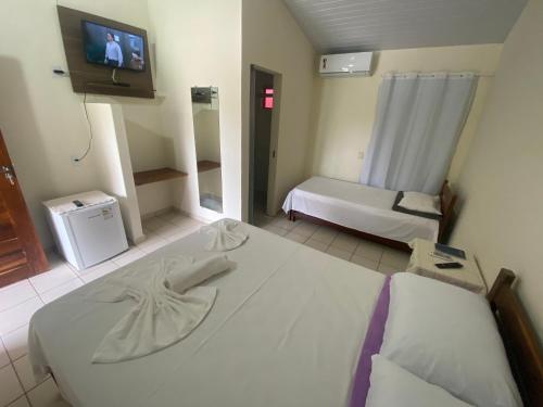 um quarto com duas camas e uma televisão na parede em Pousada Rubbi Violeta em Alto Paraíso de Goiás