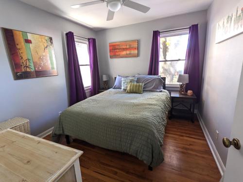 a bedroom with a bed with purple curtains and a window at Fenced backyard, deck, pet-friendly home in Springfield