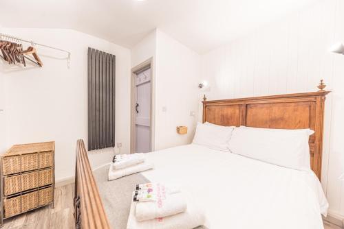 1 dormitorio con cama blanca y cabecero de madera en Romantic getaway, little two bed, two bath barn conversion with amazing views and parking, en Ambleside