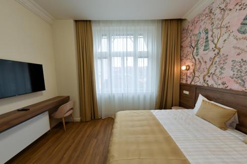 a hotel room with a bed and a flat screen tv at Leda Residence in Oradea