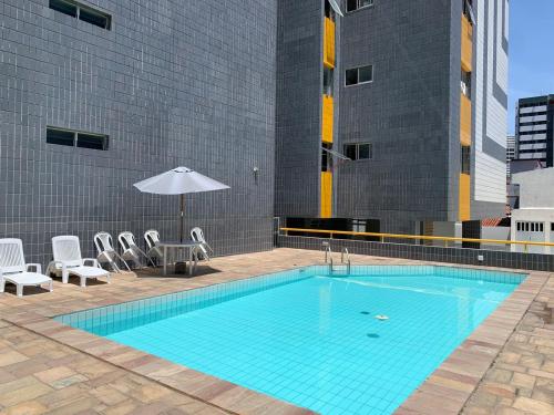 uma grande piscina com cadeiras e um guarda-sol em Apartamento 3 quartos equipado em Maceió