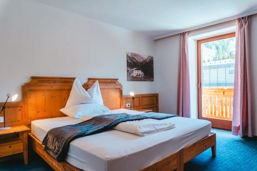 a bedroom with a large bed with a large window at Dolomitenhotel Weisslahnbad in Tires