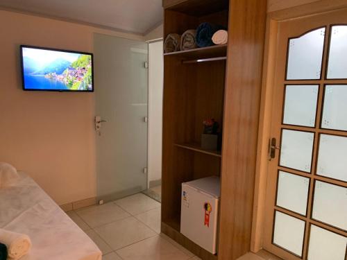 a room with a tv on the wall and a door at Pousada Perola da Praia in Penha