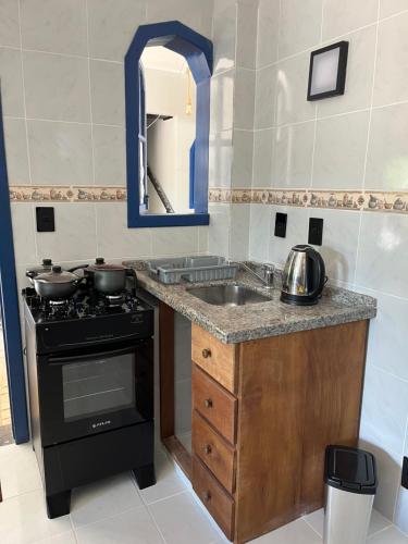a kitchen with a sink and a stove and a mirror at Pousada Maikai Garden in Porto Belo