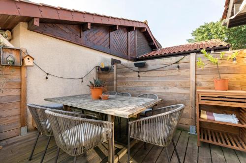 un patio avec une table et des chaises sur une terrasse dans l'établissement Superbe Villa Patio rénovée à Capbreton aux portes d'Hossegor, à Capbreton