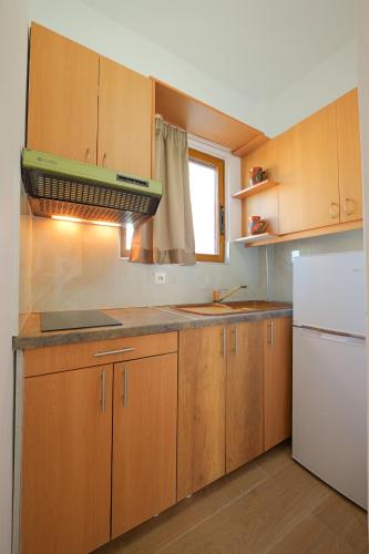 a kitchen with wooden cabinets and a white refrigerator at Villa Abedini in Ksamil