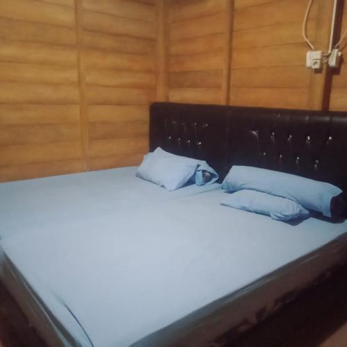 uma cama com duas almofadas azuis em cima em Karang Besi Losmen em Biha