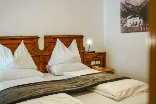 a bedroom with two beds with white pillows at Dolomitenhotel Weisslahnbad in Tires