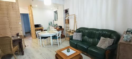 salon z zieloną kanapą i stołem w obiekcie Appartement cosy à 2 pas des rues piétonnes w mieście Chalon-sur-Saône