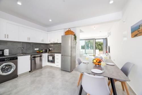 a kitchen with white cabinets and a table and chairs at PROTARAS HEIGHTS in Protaras