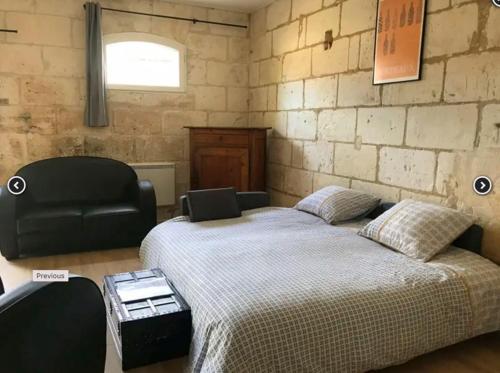 - une chambre avec un lit et une chaise noire dans l'établissement Chateau La Fontaine, à Fronsac