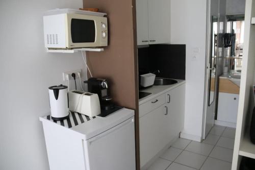 La cuisine est équipée de placards blancs, d'un four micro-ondes et d'un évier. dans l'établissement Studio 653, Port Nature 6 au village naturiste, au Cap d'Agde