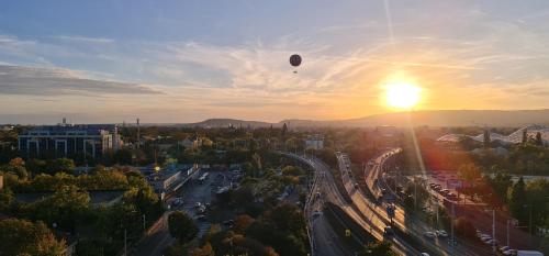 een heteluchtballon die bij zonsondergang over een stad vliegt bij Rooftop Panorama - AC, 4ppl, TV in Boedapest