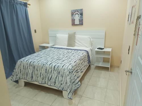 a bedroom with a bed with a black and white comforter at Apartahotel MACADANA in Nagua