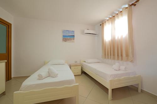 a room with two beds and a window at Villa Abedini in Ksamil
