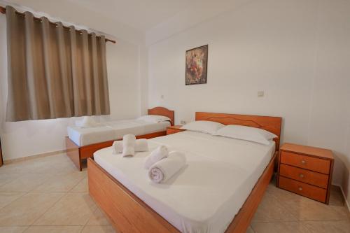 a bedroom with two beds with white sheets and towels at Villa Abedini in Ksamil